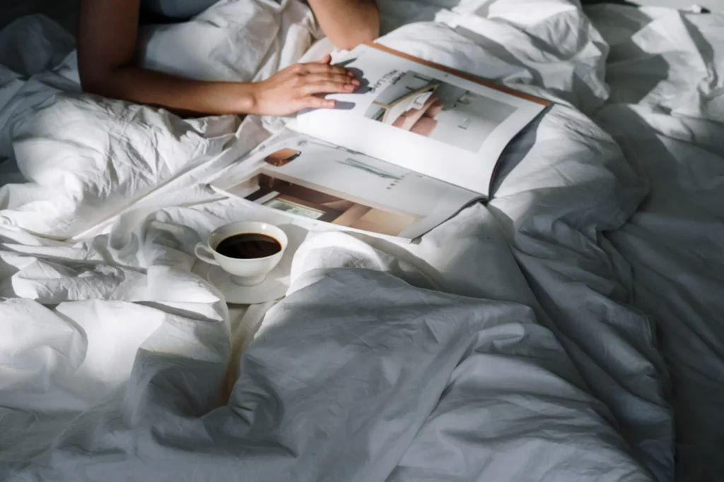 Person reading a magazine in an unmade bed
